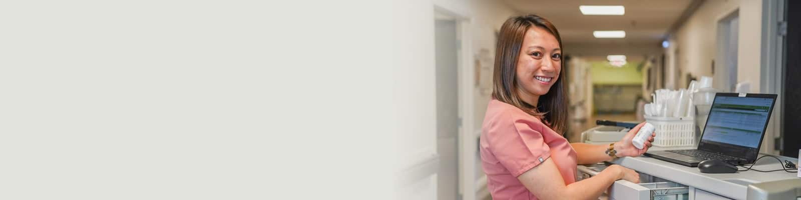 A nurse standing at the Nurses' cart in the hallway at Central Gardens Post Acute