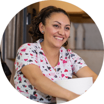 smiling woman with dark hair and a blouse with a multi-colored hearts pattern